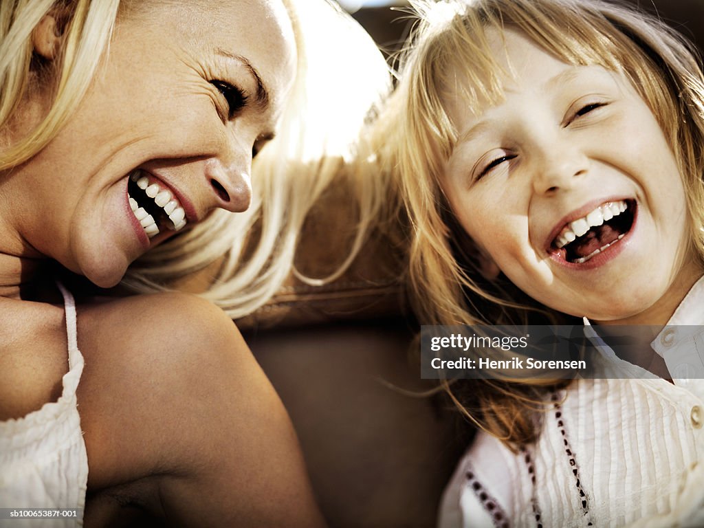 Mother and daughter (6-7) laughing, close-up