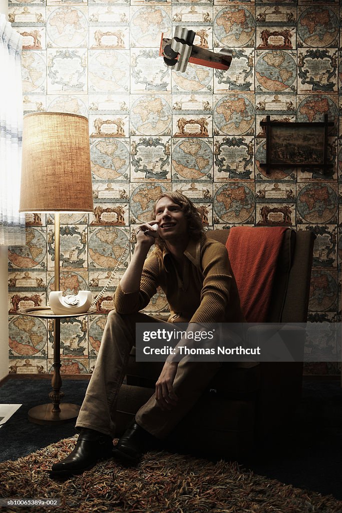 Man sitting in chair in room, talking on phone