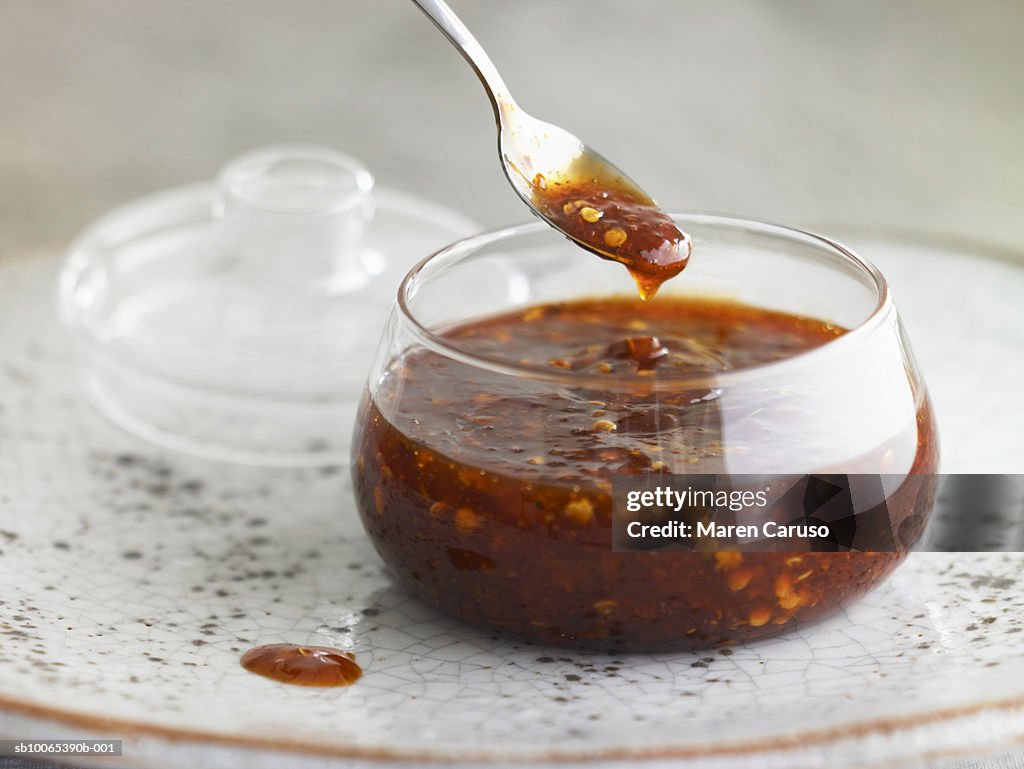 Asian hot sauce in glass bowl with lid and spoon