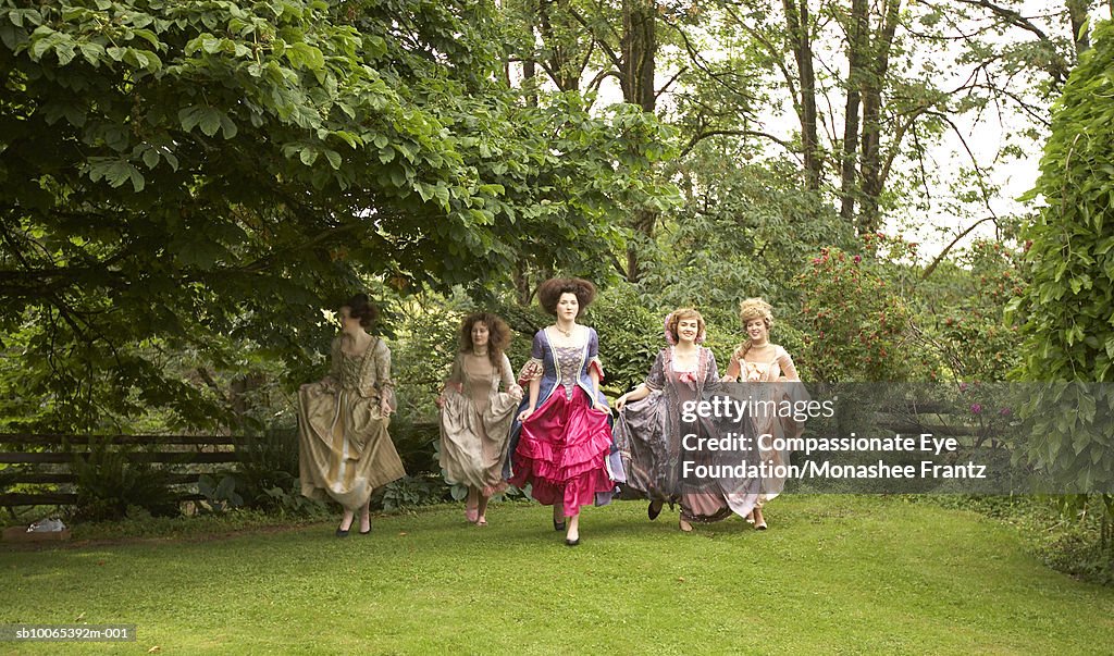 Five young women in period dresses running outside