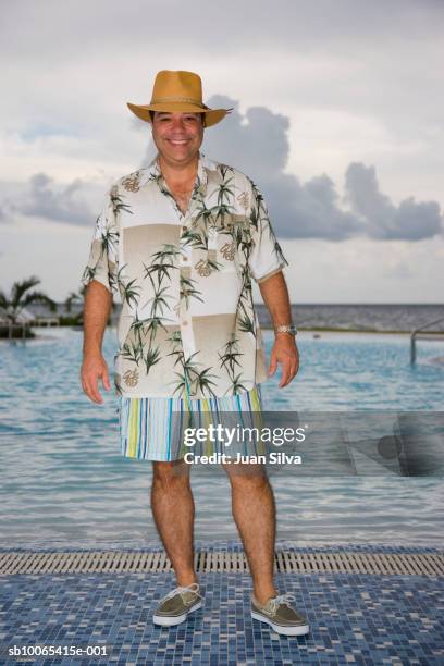 man with hat and tropical shirt by pool, smiling portrait - hawaiian shirt imagens e fotografias de stock