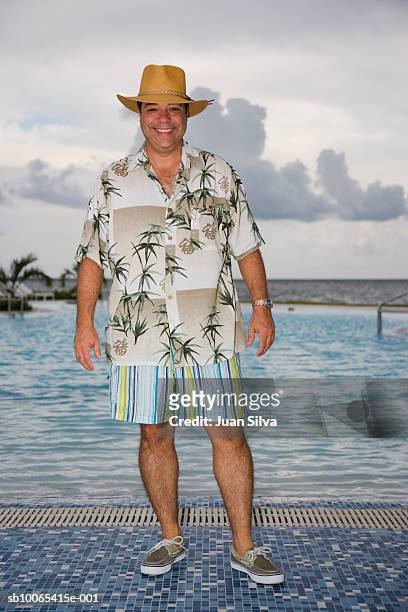 man with hat and tropical shirt by pool, smiling portrait - hawaiian shirt 個照片及圖片檔