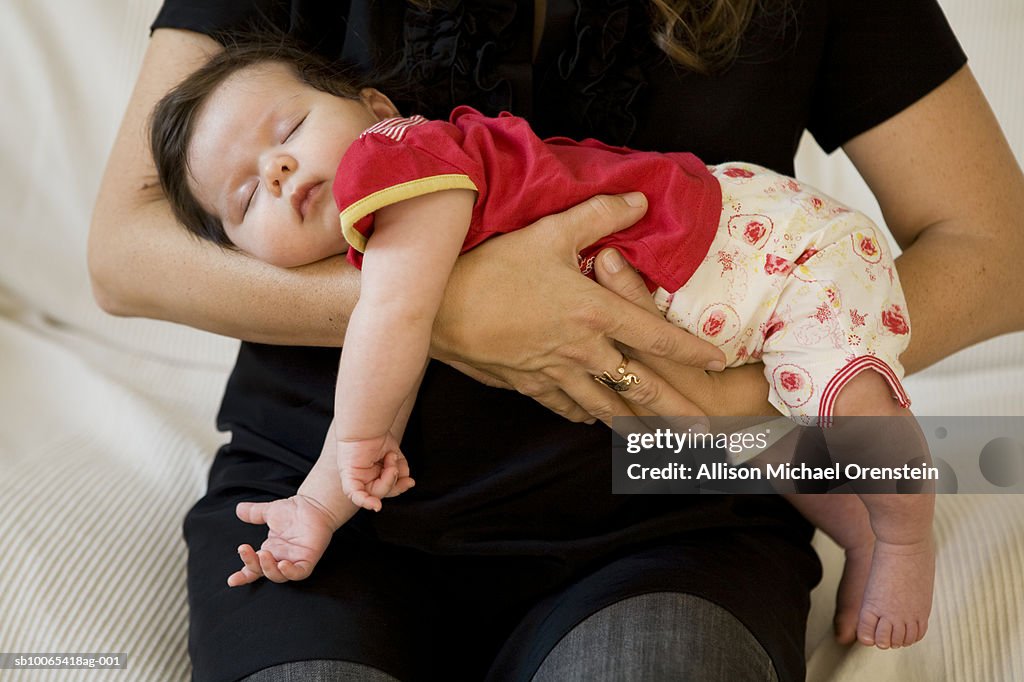 Woman holding sleeping baby (1-3 months), mid section