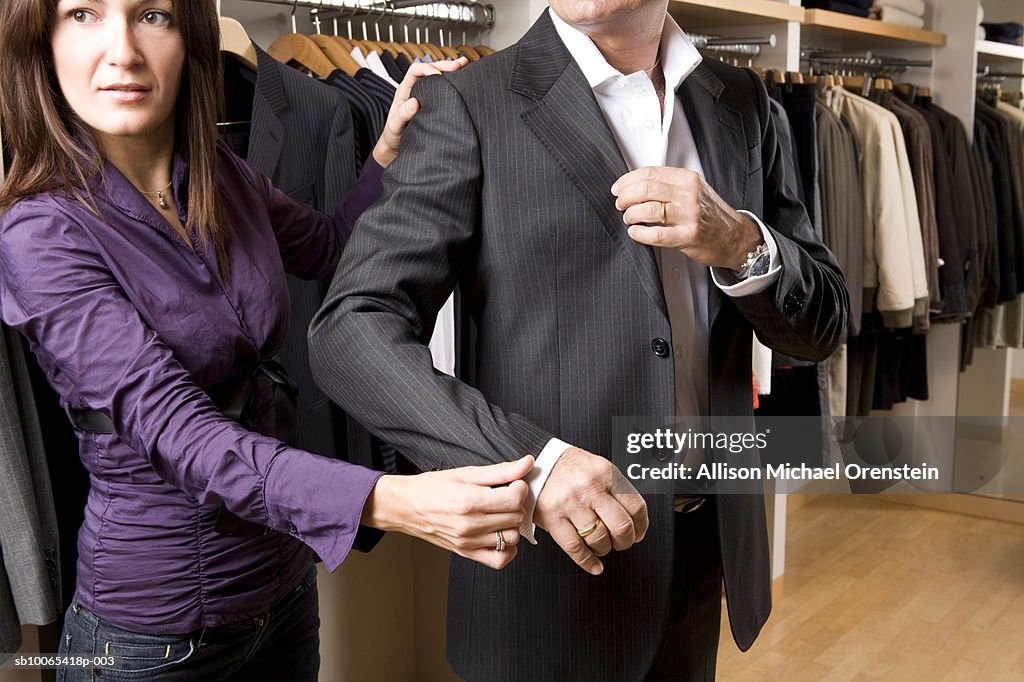 Sales woman helping customer in clothing store with suit