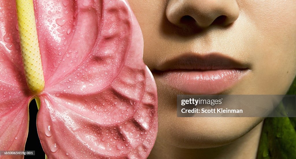 Close-up of young woman's face with Anthurium flower