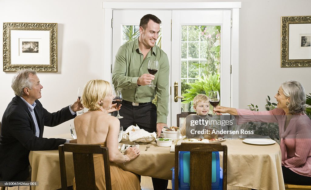 Family toasting at Dinner Table with baby girl (9-12 months) and boy (2-3 years) looking on