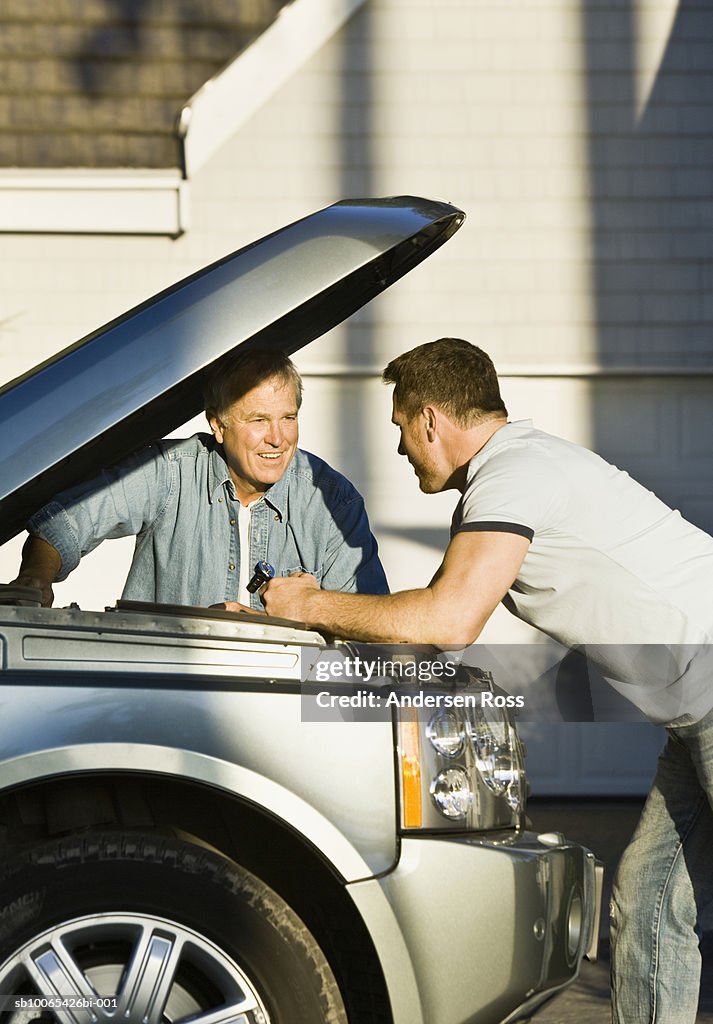 Two men examining engine of car