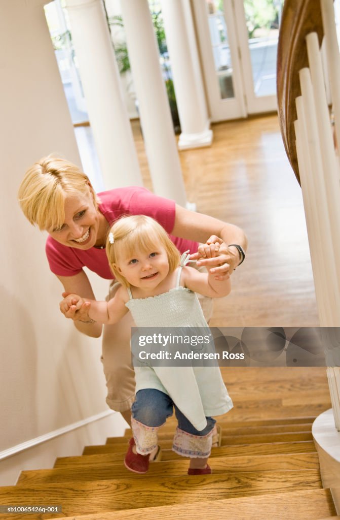 Mother and baby daughter (9-12 months) walking up staircase