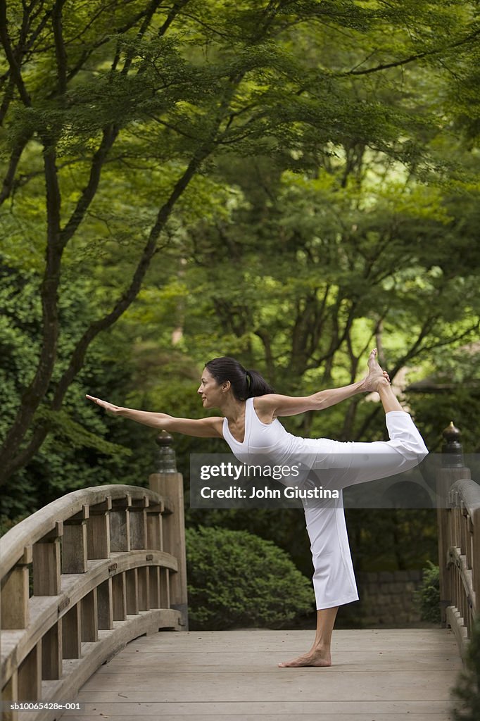 Woman performing yoga on bridge in Japanese garden