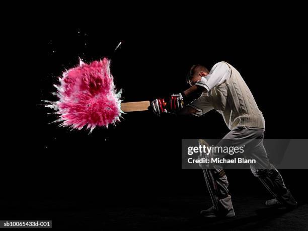 batsman hitting exploding powder ball, side view, studio shot - batting foto e immagini stock