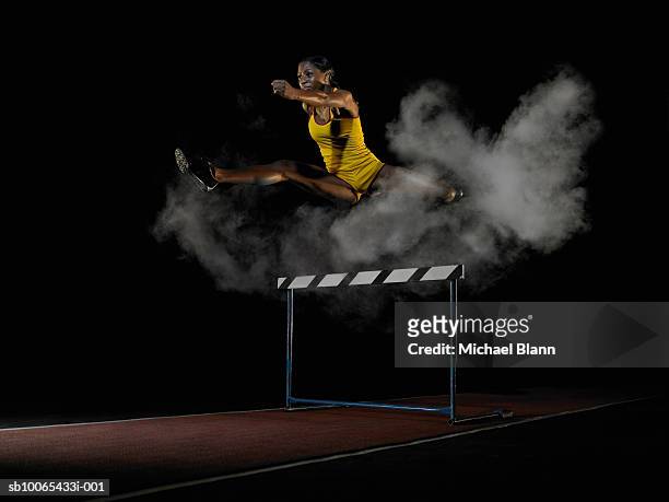 female runner running in cloud of smoke, studio shot - hurdling track event fotografías e imágenes de stock