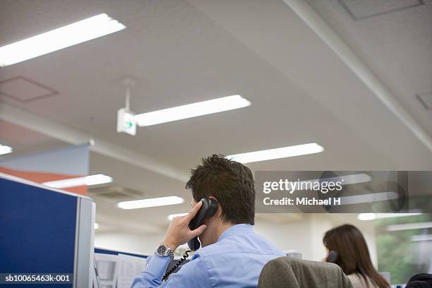 men using landline phone in office - luce fluorescente foto e immagini stock
