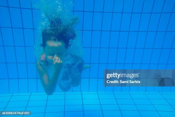 girl (6-7) diving in swimming pool, holding nose, underwater view - 鼻をつまむ ストックフォトと画像