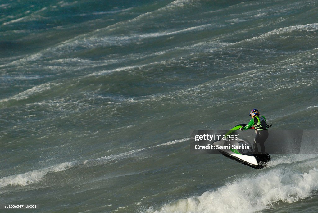Man jumping on waves with jet-ski, elevated view
