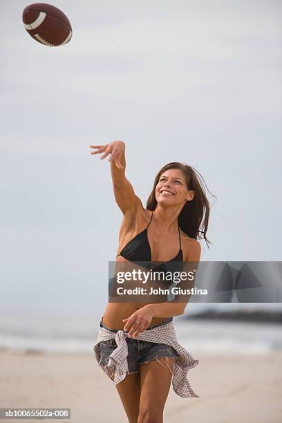 young woman throwing american football on beach - football américain femme photos et images de collection