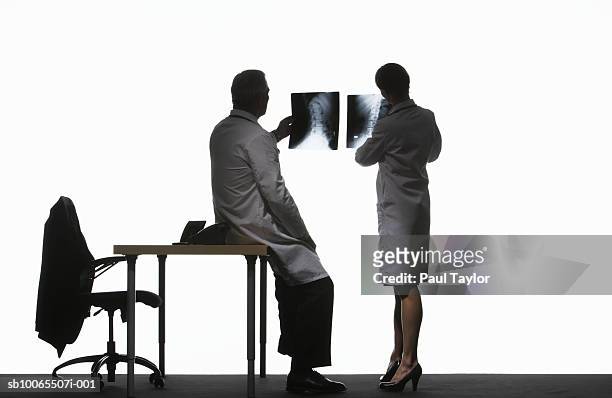 two doctors looking at x-ray image, rear view - back lit doctor stock pictures, royalty-free photos & images
