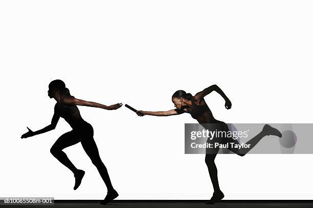 two women passing relay baton - relay fotografías e imágenes de stock