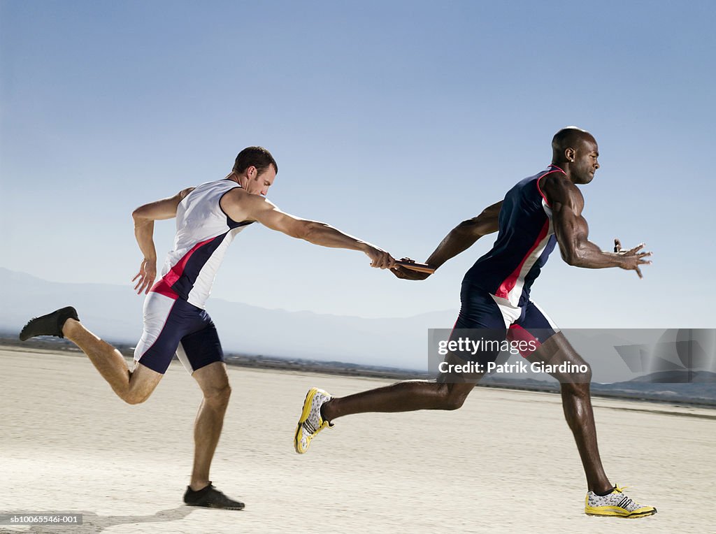 Two athletes passing relay, side view