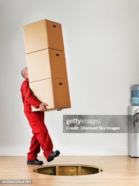 man carrying stack of boxes, falling in hole of wooden floor - skybox stockfoto's en -beelden