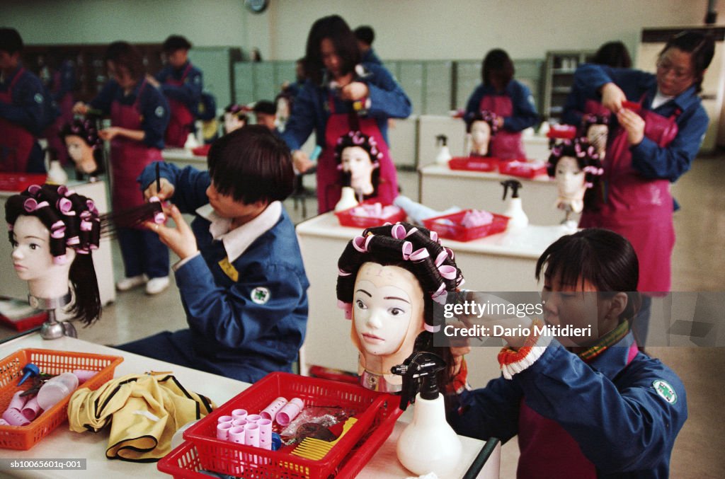 Teenage girls (16-17) in classroom during hairdressing lesson