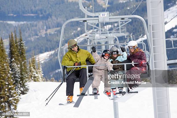 family with two kids (6-7) on chairlift with skis - couple ski lift stockfoto's en -beelden
