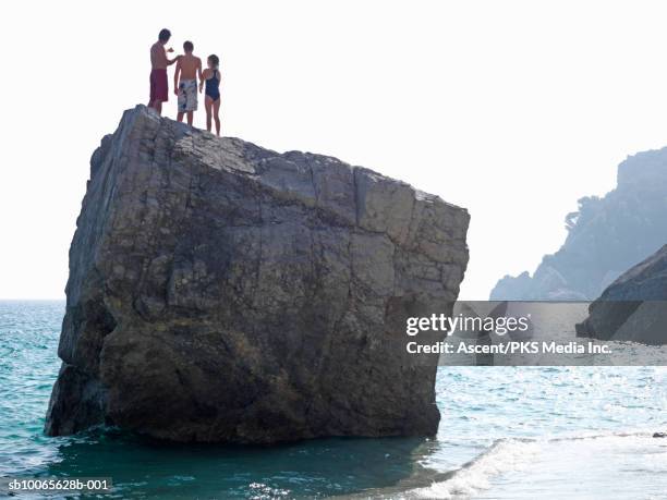 three people standing on big rock in ocean - preteen girl no shirt stock pictures, royalty-free photos & images