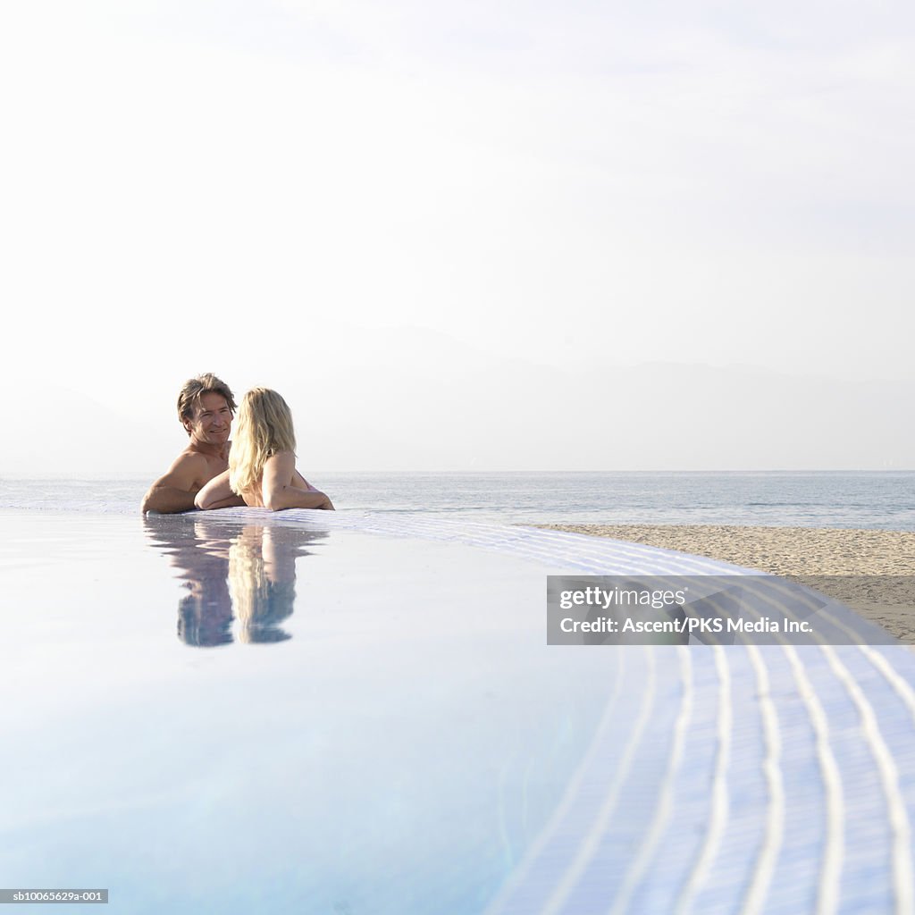 Mature couple leaning at edge of infinity pool