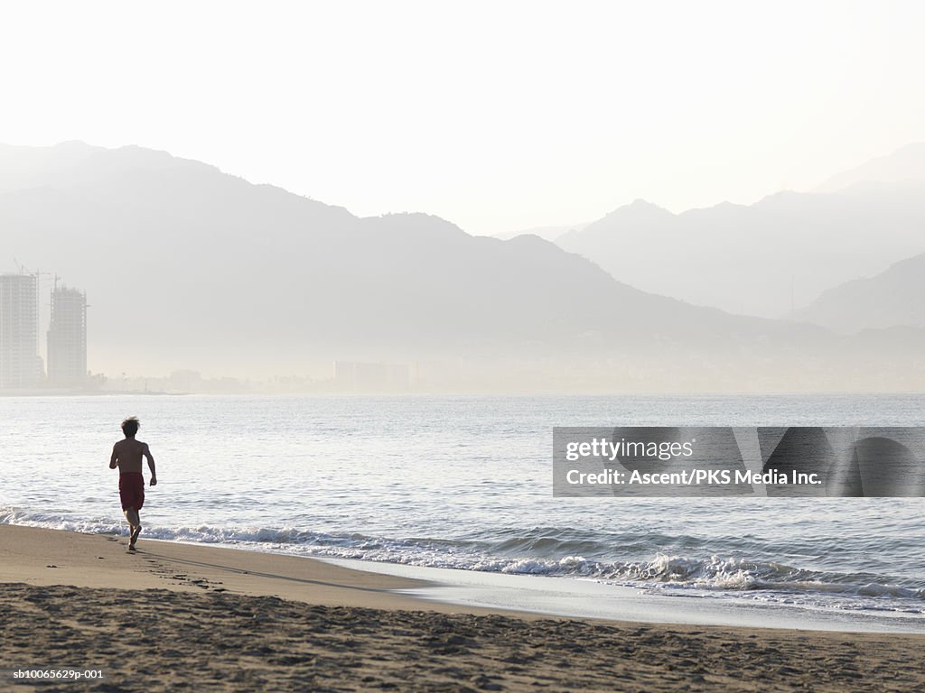 Man running on beach, rear view