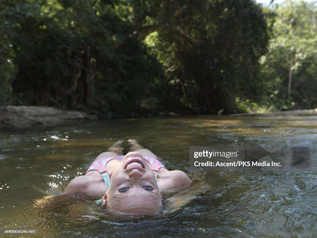 Mature woman floating in river, smiling