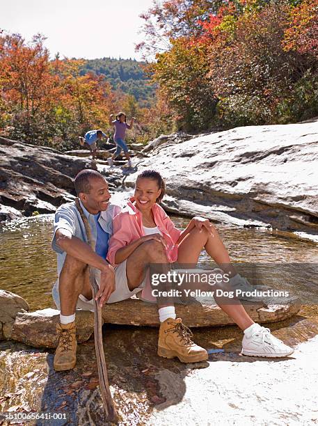 parents sitting on rocks, children (10-13) in background - asheville stock pictures, royalty-free photos & images