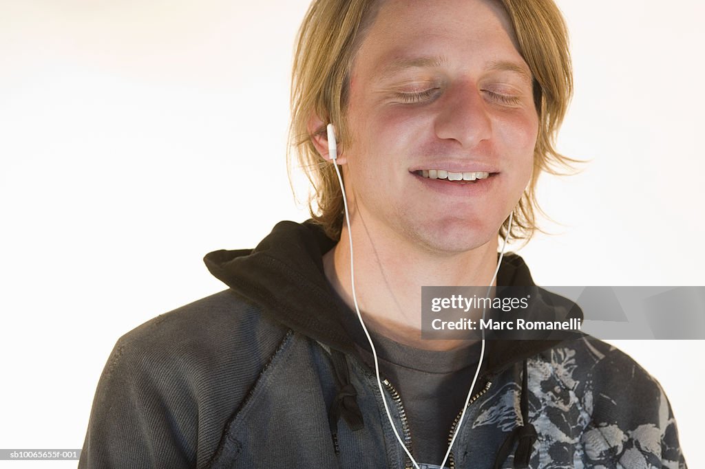 Young man with eyes closed, wearing earphones