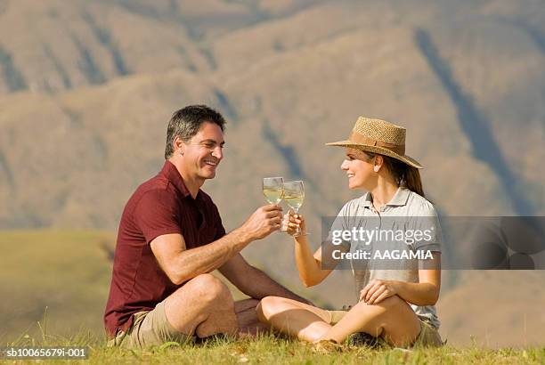 mature couple sitting on grass toasting wine glass - serra da canastra national park stock pictures, royalty-free photos & images