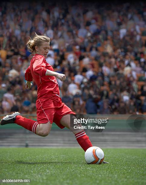 female soccer player kicking ball in sports stadium - woman football stock-fotos und bilder
