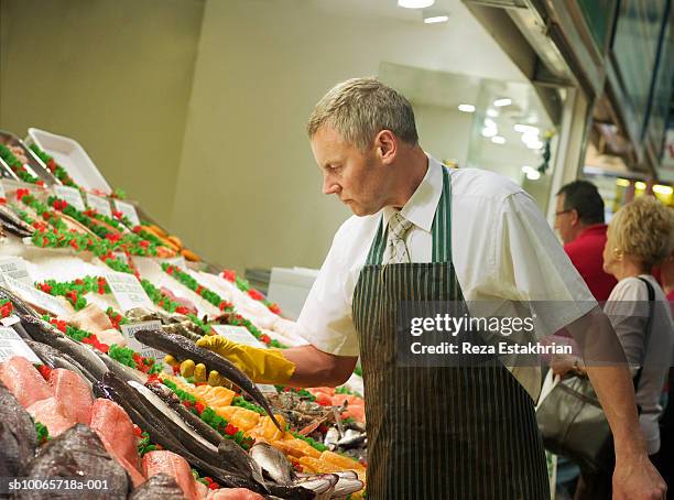 fishmonger selecting fish from stall - fishmonger stock pictures, royalty-free photos & images