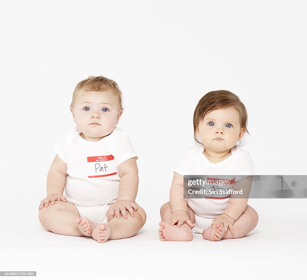 Two babies (6-9 months) sitting on white background