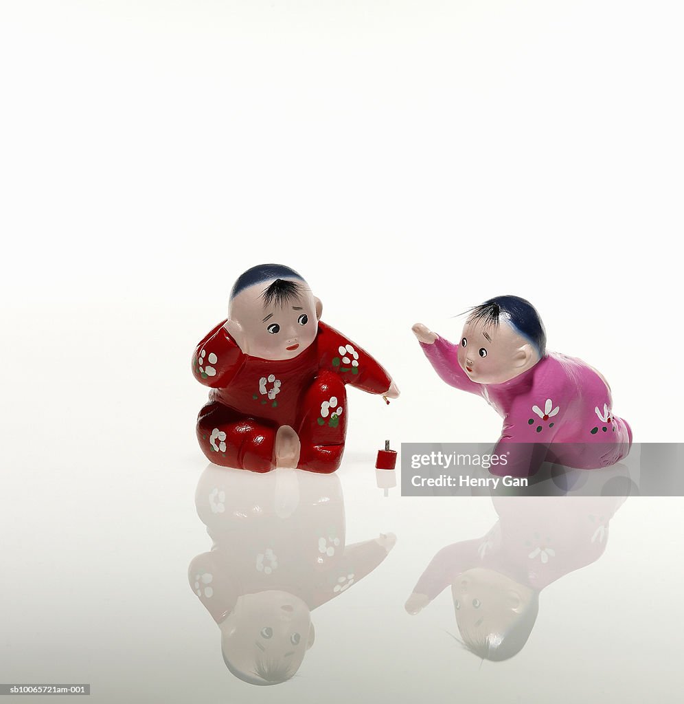 Two ceramic toy figurines of children playing with ball, studio shot