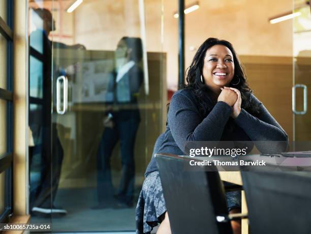 businesswoman at conference table, colleague in background - native african ethnicity stock-fotos und bilder