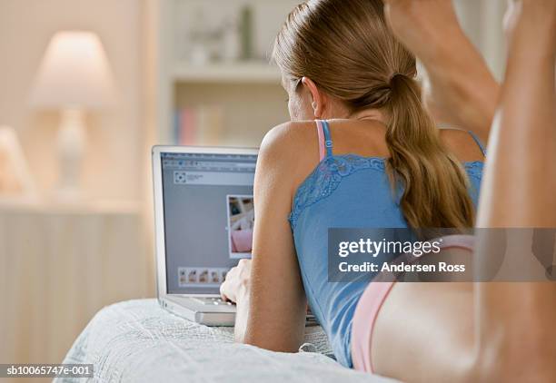 young woman using laptop, lying on bed, rear view - lying on back ストックフォトと画像