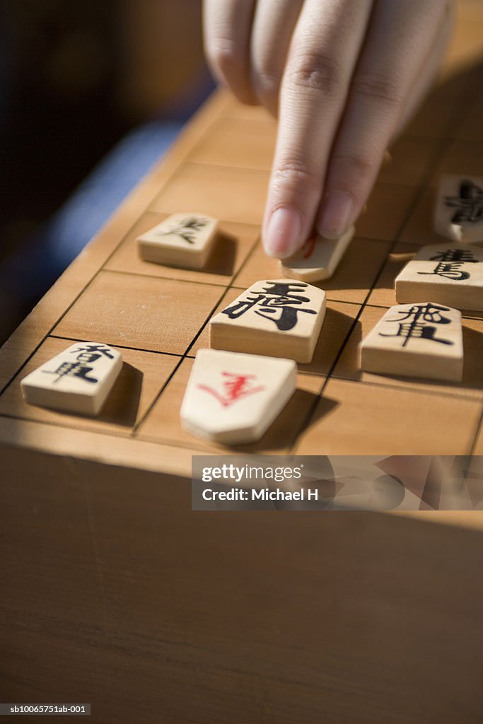 Human hand moving koma on shogi board