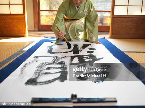 Japan, Tokyo,woman wearing kimono writing calligraphy on large piece of paper Japan, Tokyo,woman wearing kimono writing calligraphy on large piece of paper