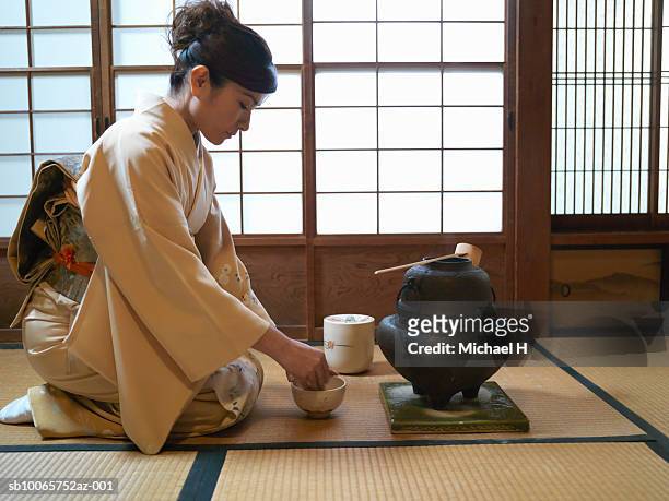 japan, tokyo, woman kneeling on floor, preparing tea, side view - feierliche veranstaltung stock-fotos und bilder
