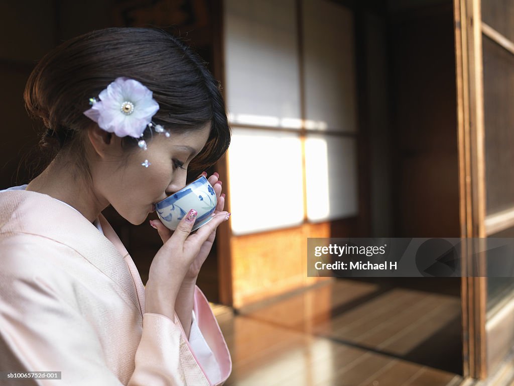 Japan, Tokyo, woman  in kimono drinking tea, side view