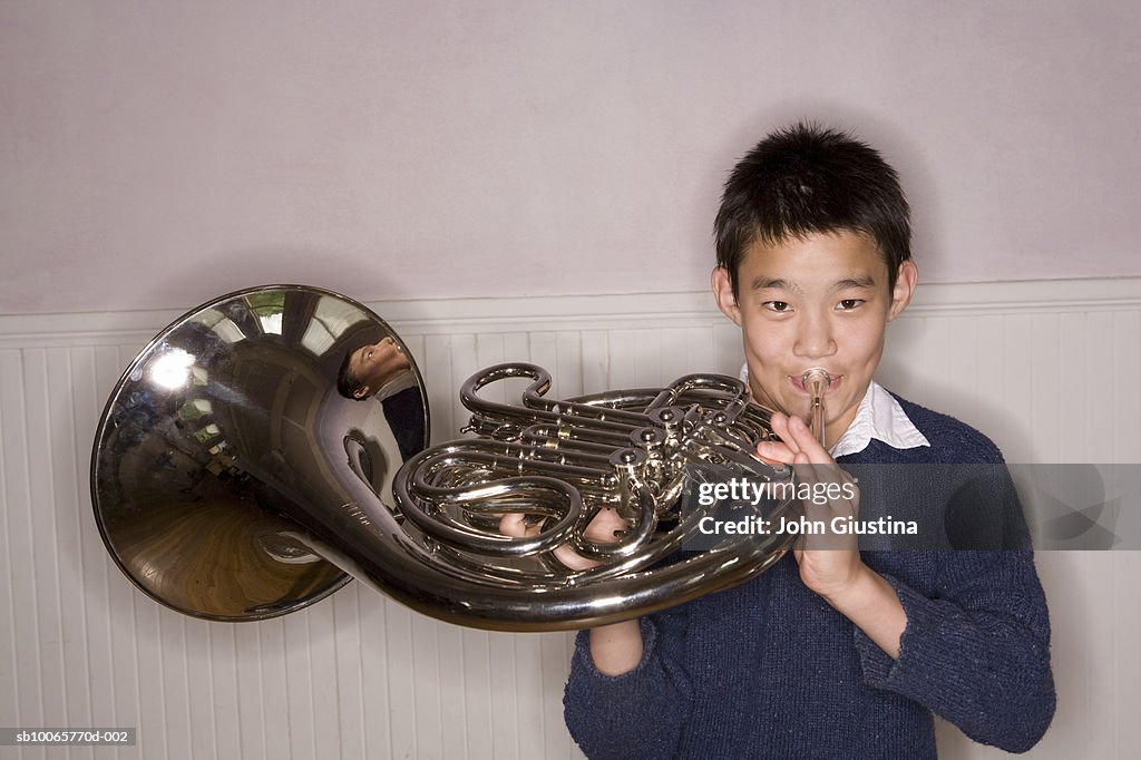 Teenage boy (14-15) playing french horn, portrait