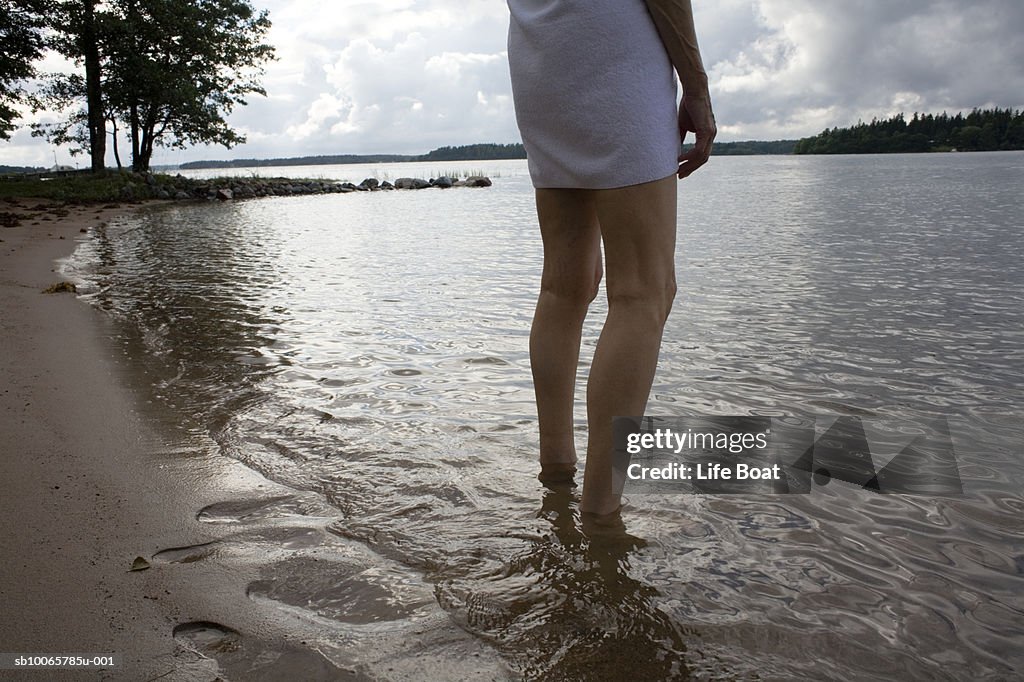 Woman standing in lake, low section