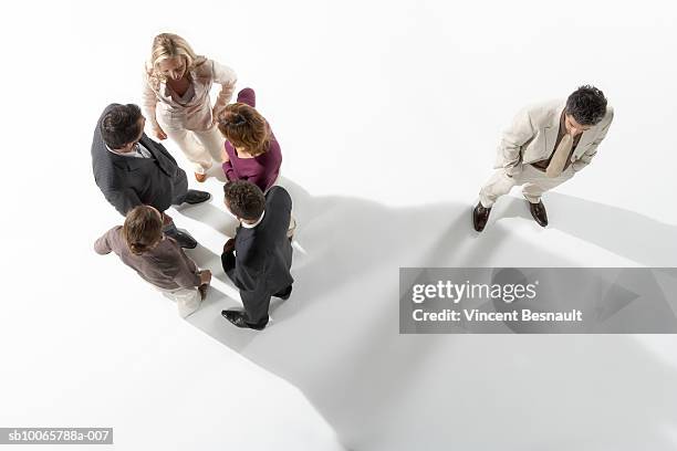 isolated business man standing away from group of business people - office politics stockfoto's en -beelden