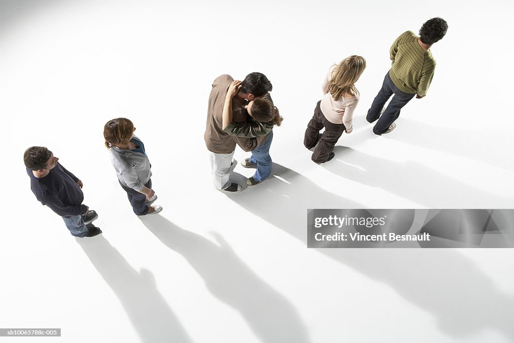 Couple embracing whilst standing in line with group of people