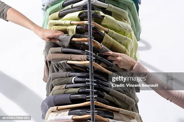 two female hands holding same shirt hanging from clothes rack - clothing store stockfoto's en -beelden