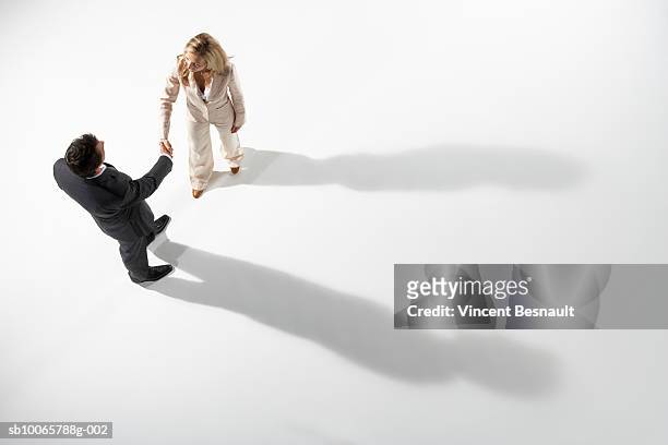 business man and woman exchanging handshake, shadow showing otherwise - abmachung stock-fotos und bilder