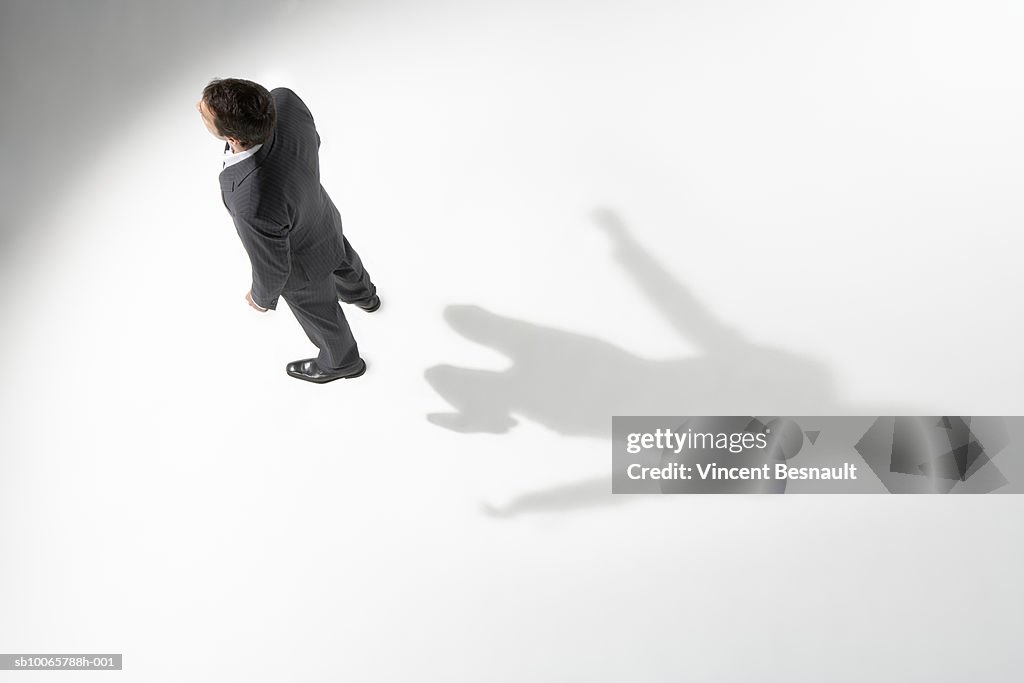 High angle view of business man standing, shadow showing him jumping