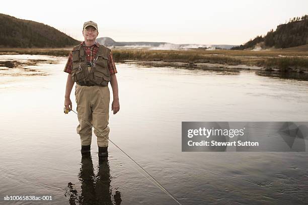 portrait of senior man in river with fishing rod - fiskeväst bildbanksfoton och bilder